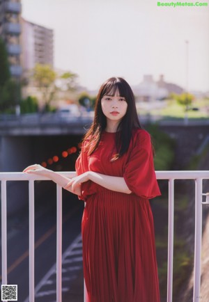 A woman in a red dress standing on a beach.