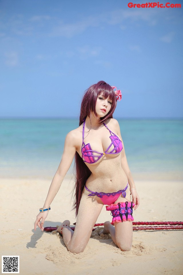 A woman in a bikini sitting on the beach.