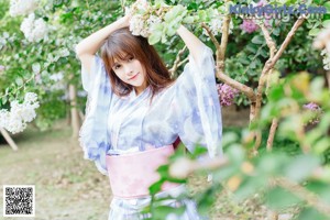 A woman in a blue and pink kimono leaning against a railing.