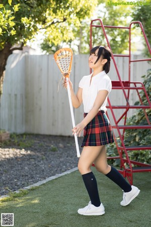 A woman in a school uniform holding a broom.