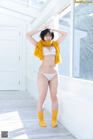 A woman in a white bikini sitting on a wooden floor.