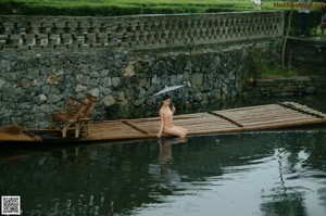 A naked woman standing on top of a wooden structure.