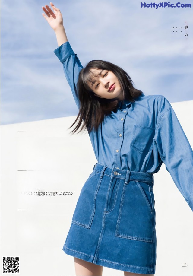 A woman in a blue shirt dress is posing for a magazine.