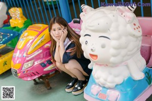 A woman in a school uniform standing next to a carousel.