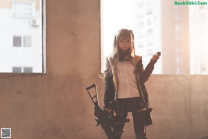 A woman in a black and yellow outfit holding a gun.