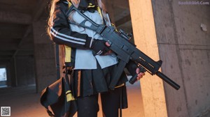 A woman in a black and yellow outfit holding a gun.