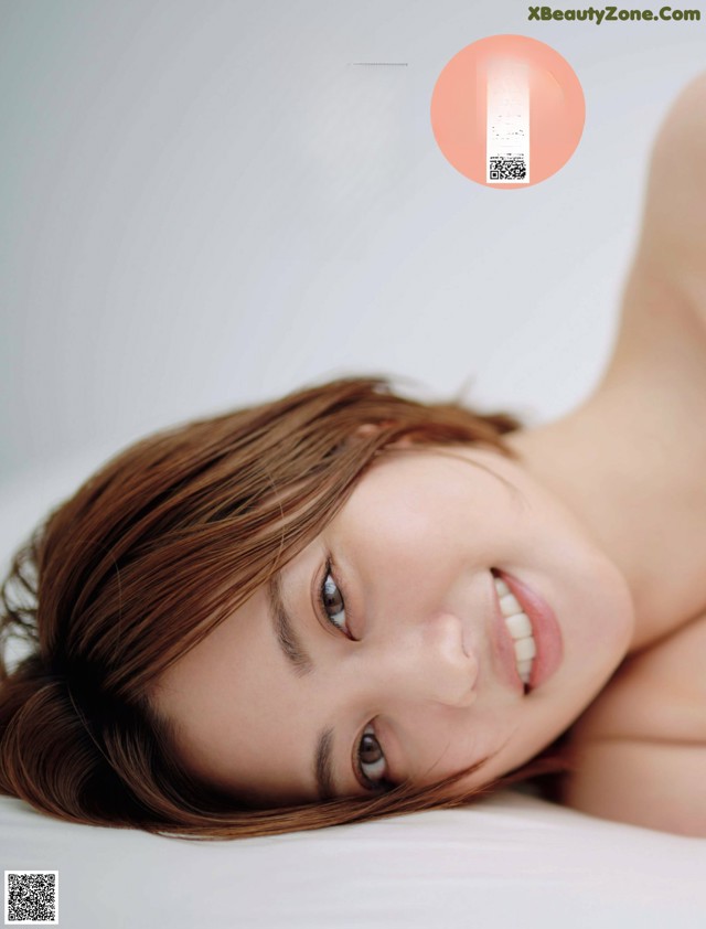 A woman laying on top of a bed smiling.