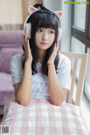 A woman in a cat ears headband holding a pink and white pillow.