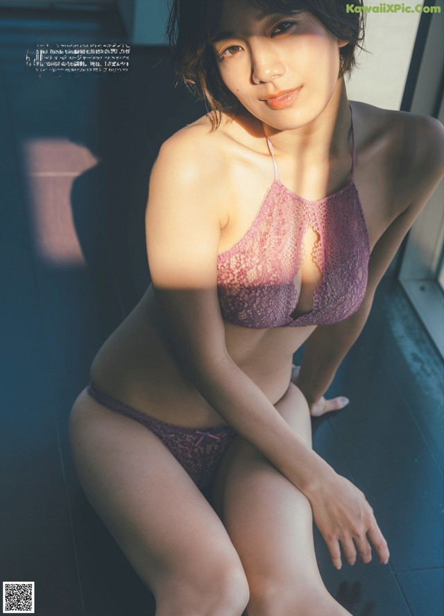 A woman in a purple lingerie sitting on a window sill.