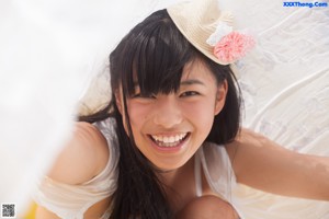 A young girl in a straw hat eating a strawberry.