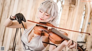 A woman in a white dress holding a violin.