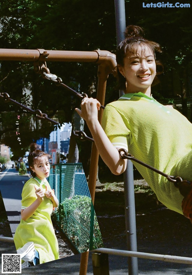 A woman in a green shirt is swinging on a swing set.