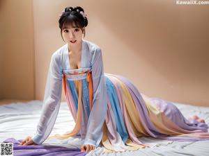 A woman in a beige robe is posing for the camera.