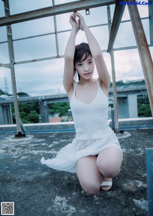 A woman in a white dress is standing on a rock.