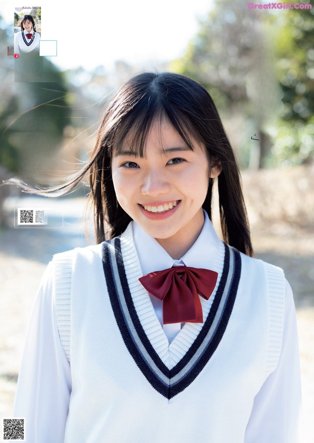 A young woman in a school uniform smiles at the camera.