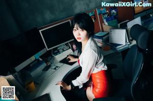 A woman in a red lingerie sitting on a desk.