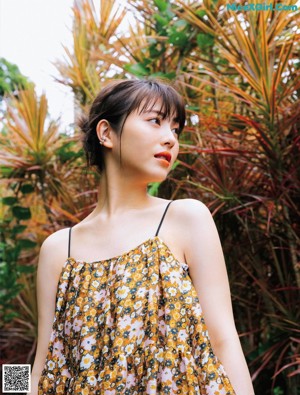 A woman holding a red flower in front of her face.