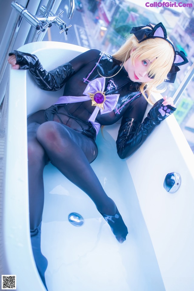 A woman in a black cat suit sitting in a bathtub.