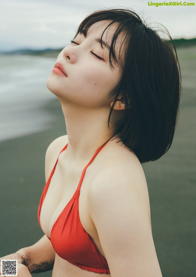 A woman in a red bikini standing on a beach.