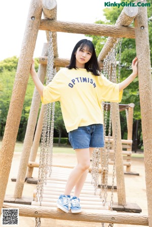 A young woman sitting on a seesaw in a park.