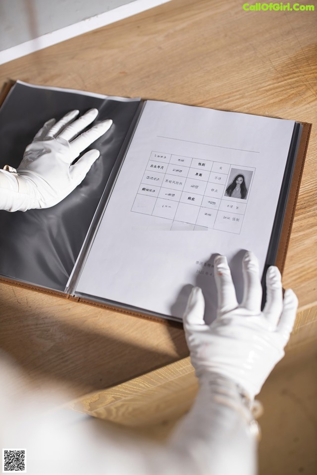 A person in white gloves holding a book on a table.