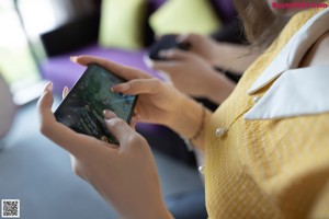 A woman in a yellow dress looking at her cell phone.