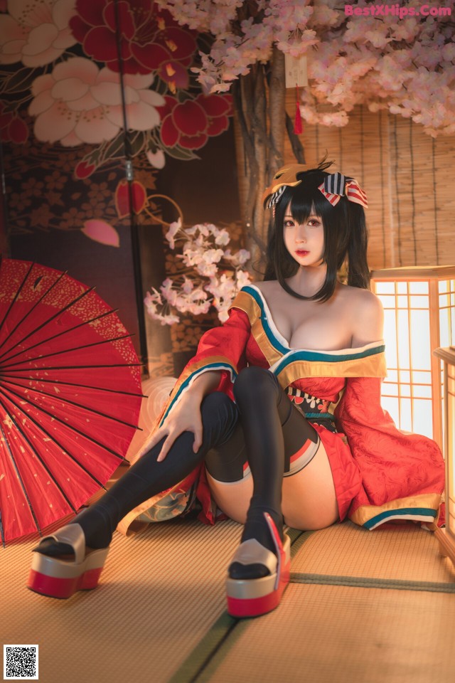 A woman in a red kimono sitting on the floor with an umbrella.