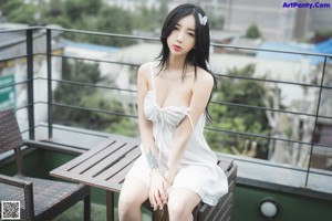 A woman in a white lingerie sitting on a window sill.