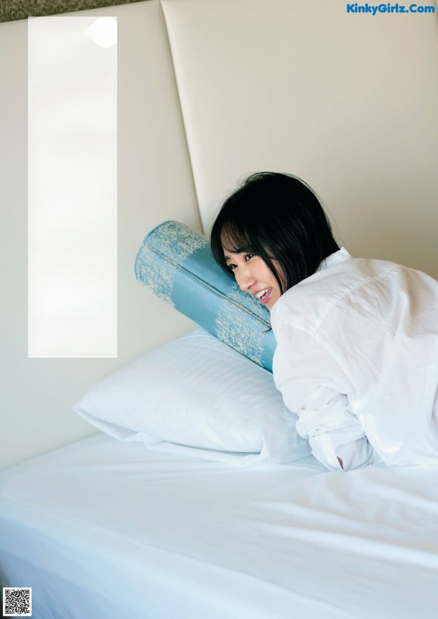 A woman laying on a bed with a pillow on her head.