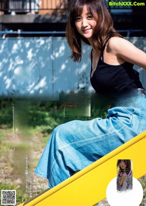 A woman in a blue shirt and white panties sitting on a blue chair.