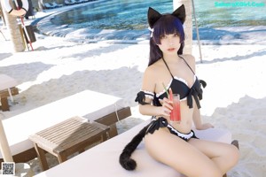 A woman in a black and white bikini sitting on a beach.