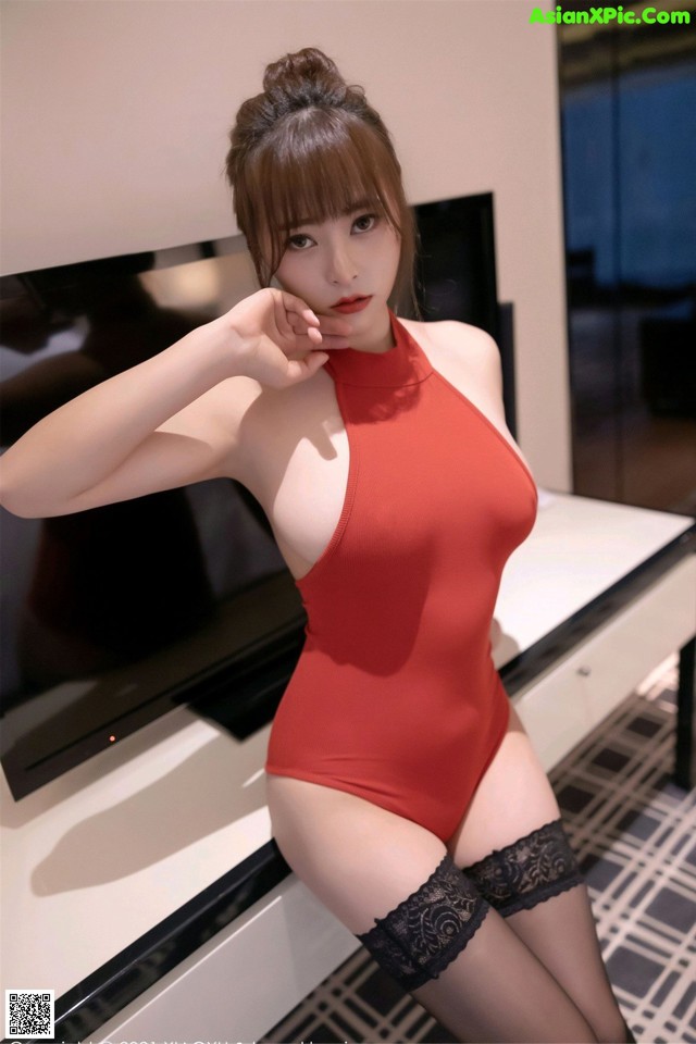 a woman in a red bodysuit and stockings posing for the camera