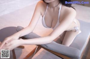 A naked asian woman leaning against a wall in a room.