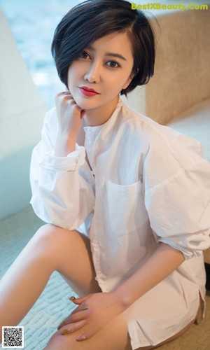 A woman in a white shirt is sitting on a couch.