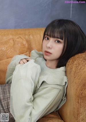 A woman sitting on top of a brown couch.