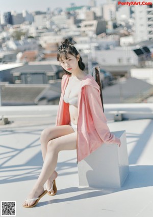 A woman in a pink dress standing on top of a building.